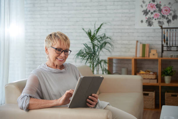 starsza kobieta z cyfrowym tabletem - old armchair women senior adult zdjęcia i obrazy z banku zdjęć