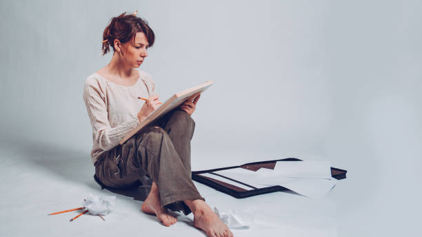 istock Good-looking cheerful professional young female artist working on a new creative project, drawing, making sketches with pencil, People, job, occupation, profession and hobby concept 945422932