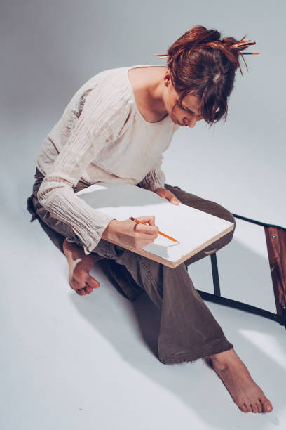 istock Good-looking cheerful professional young female artist working on a new creative project, drawing, making sketches with pencil, People, job, occupation, profession and hobby concept 945423030