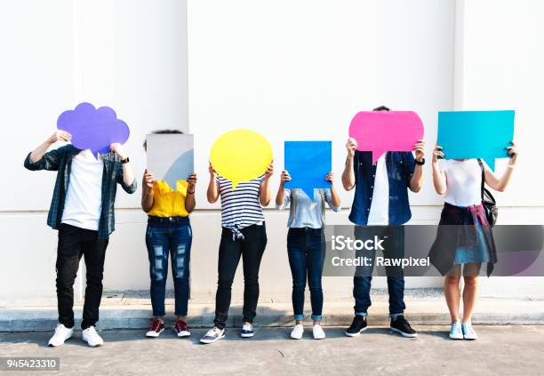 Young Adult Friends Holding Up Copy Space Placard Thought Bubbles Stock Photo - Download Image Now