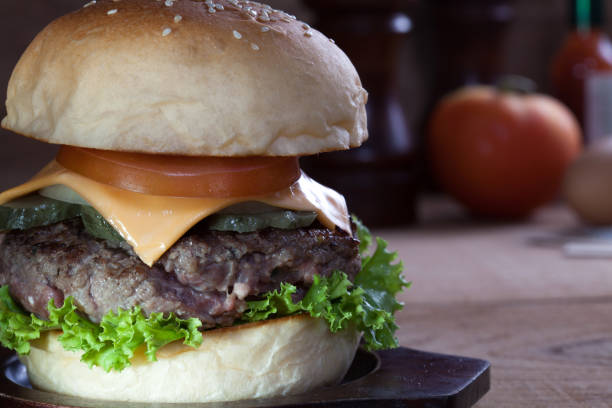 istock Close up of beef burger with cheese on wood table. 945423706