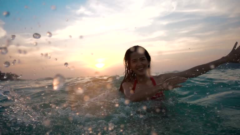 Asian sexy girl in bikini with wet hair and lips Having Fun Splashing in the sunset at sea