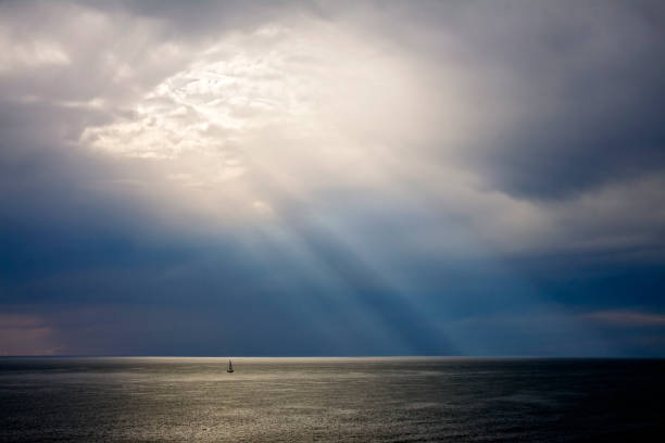 Sunbeams sunset on mediterranean sea with sail boat