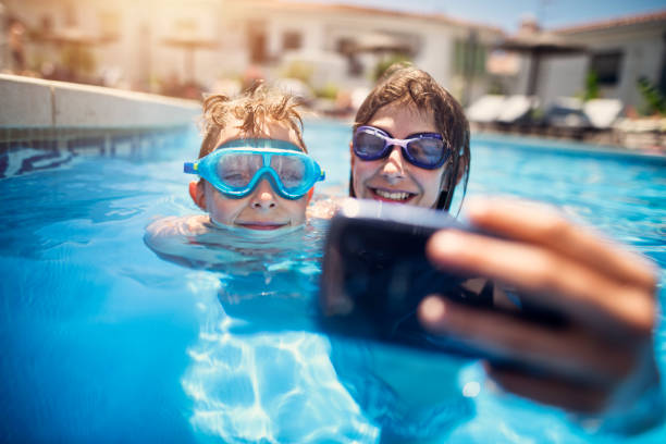istock Brother and sister taking selfie in pool 945427478