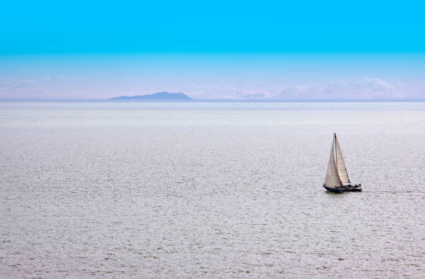 Fiberglass newer model sailboat comes up on a stern at sea of Southern California waters in the Santa Monica Bay, three unrecognizable people