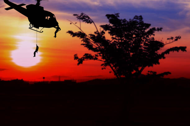 istock soldier silhouette in rappelling climb down from helicopter on sunset with copy space add text ( Concept stop hostilities To peace) 945428138