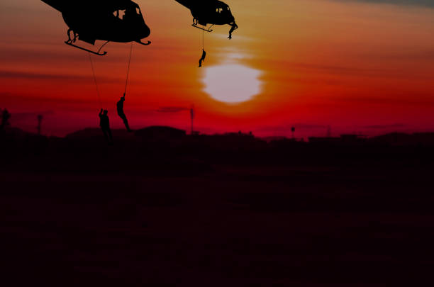 istock Silhouette Soldiers rappel down to attack from helicopter with sunset Background blur and copy space add text ( Concept stop hostilities To peace) 945431422