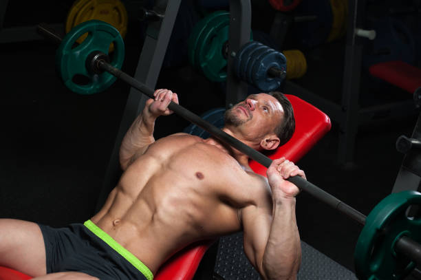 istock Man athlete exercising in the gym with a barbel 945439072