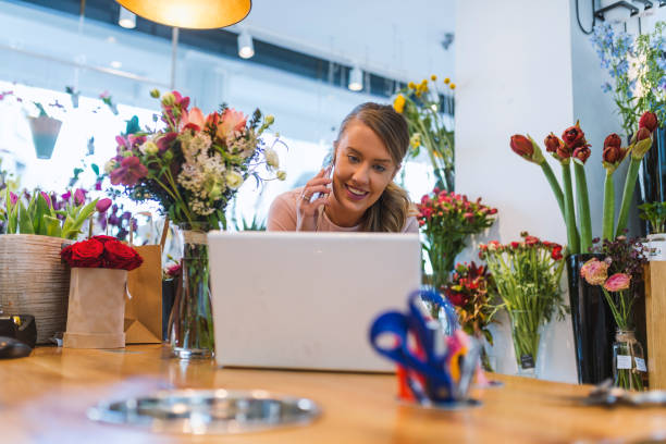 istock Florist talking on mobile phone and using laptop 945439462