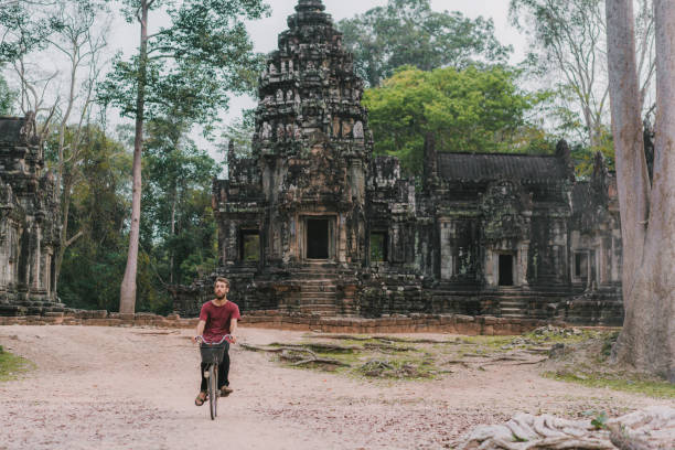 istock Young Caucasian man riding  bicycle  in Angkor Wat 945440404