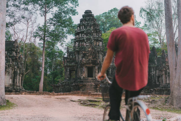 istock Young Caucasian man riding  bicycle  in Angkor Wat 945440410