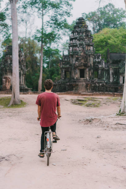 istock Young Caucasian man riding  bicycle  in Angkor Wat 945440422