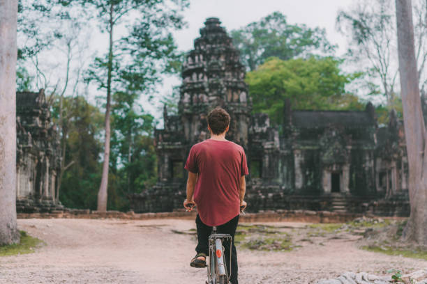 istock Young Caucasian man riding  bicycle  in Angkor Wat 945440440
