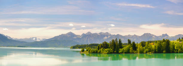 istock panoramic landscape in Bavaria with alps mountain range and lake Forggensee 945443354