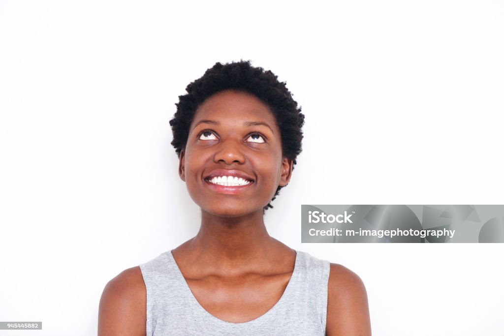 Close up young african woman looking up and smiling on white background Close up portrait of young african woman looking up and smiling on white background Women Stock Photo