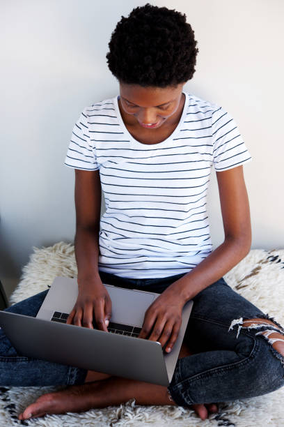 istock young african woman sitting on floor and working laptop computer 945445986