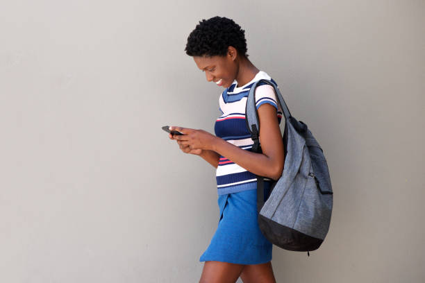 istock young woman walking with bag and using smart phone on gray background 945446068