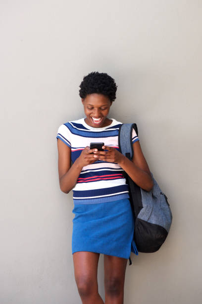 istock young african female using phone and laughing on gray background 945446084