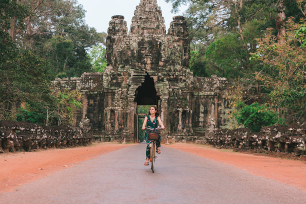 istock Young Caucasian woman riding  bicycle  in Angkor Wat 945449832