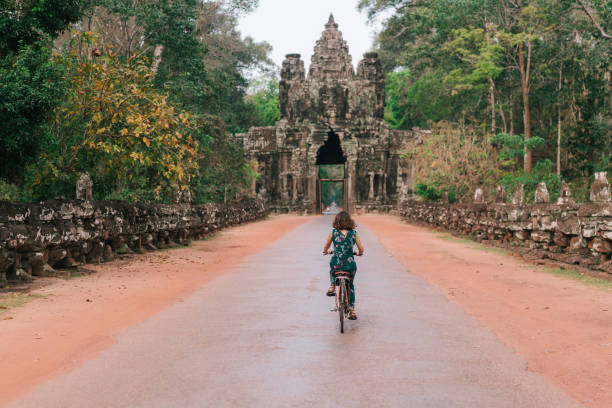 junge kaukasischen frau reiten fahrrad in angkor wat - khmer stock-fotos und bilder