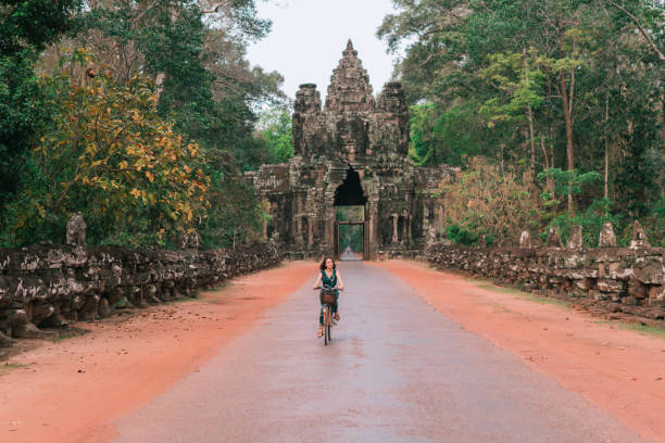 istock Young Caucasian woman riding  bicycle  in Angkor Wat 945449880