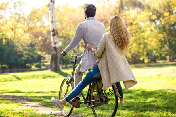 istock Young couple with bicycle having fun in park on sunny autumn day. 945451492