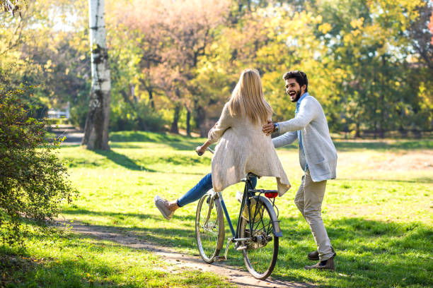 istock Young couple with bicycle having fun in park on sunny autumn day. 945451810