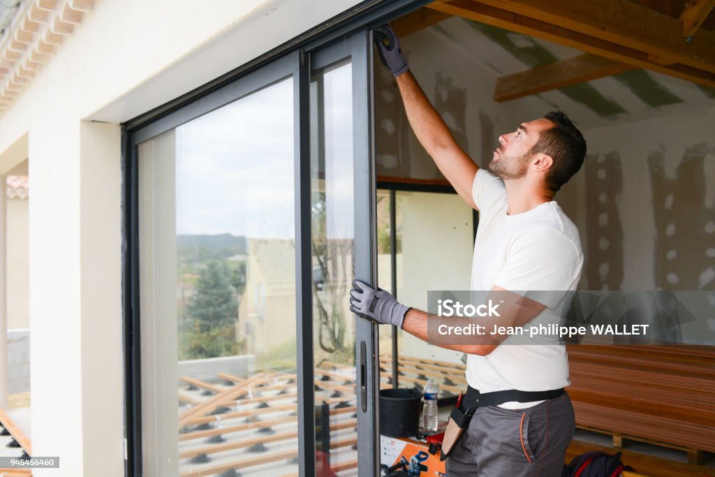 handsome young man installing bay window in a new house construction site Window Stock Photo