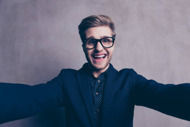 istock Young happy laughing businessman in glasses making selfie 945456638
