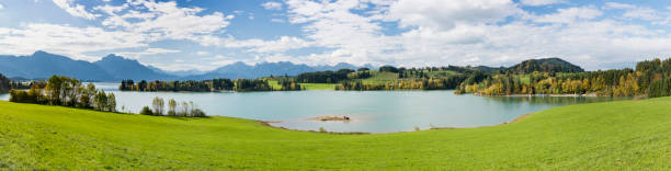 istock panoramic landscape in Bavaria with alps mountain range and lake Forggensee 945456778