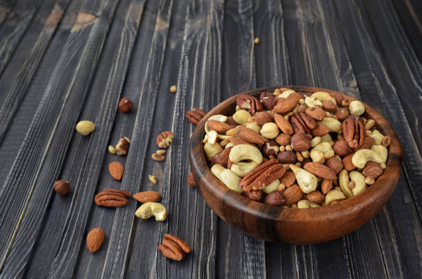 istock Nuts mix Almonds, Cashews, Macadamia, Peanuts, Walnuts, Pecans, Pine Nuts, Pistachios in a wooden plate 945470724