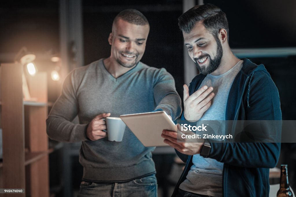 Joyful two colleagues perfecting code Do this. Delighted happy two colleagues communicating while staring at tablet screen and smiling Achievement Stock Photo