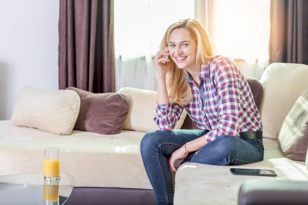 istock Woman talking on cell phone on sofa 945474760