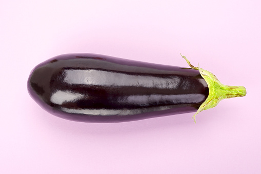 Fresh raw dark purple eggplant isolated on colored background