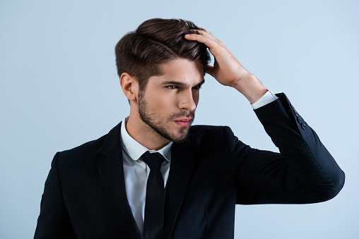 Portrait of handsome young man in black suit combing hair