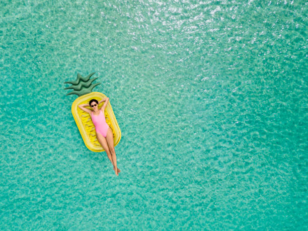 mujer despreocupada en piña inflable - lying on back fotos fotografías e imágenes de stock