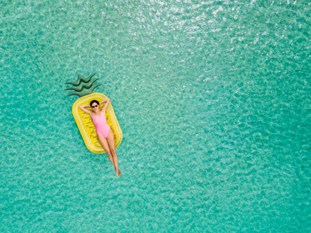 Carefree woman on inflatable pineapple Carefree woman on inflatable pineapple sunbathing photos stock pictures, royalty-free photos & images