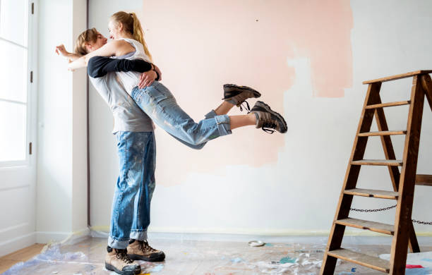 cheerful couple renovating the house - repairing apartment home improvement painting imagens e fotografias de stock