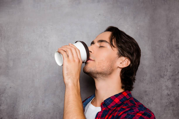 istock Portrait of young handsome man drinking coffee on gray background 945501084