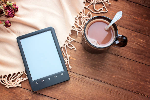 E-book reader and cup of cocoa on a wooden background selective focus
