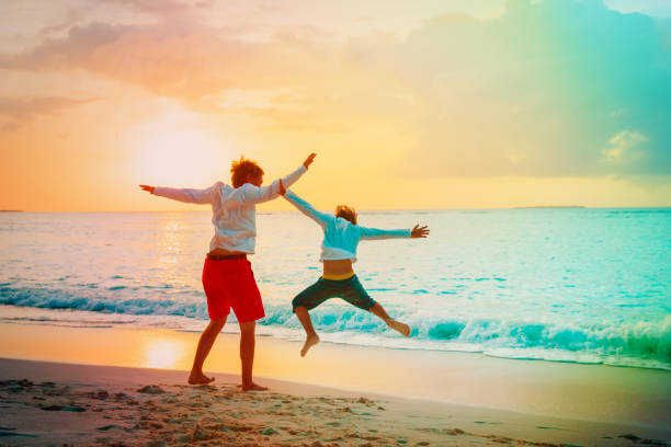 istock father and son have fun jump at sunset beach 945521498