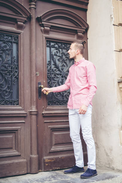 istock Young modern man in front of massive wooden door. 945545228