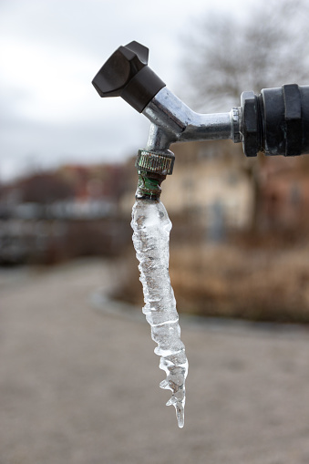 Frozen water hanging from a tap outdoors