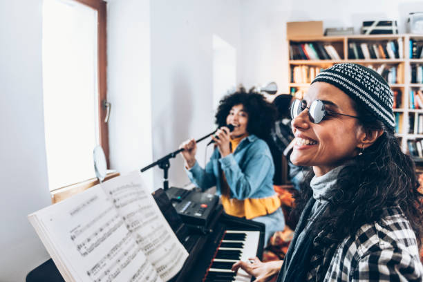 istock Young woman playing piano with friends in studio 945556016