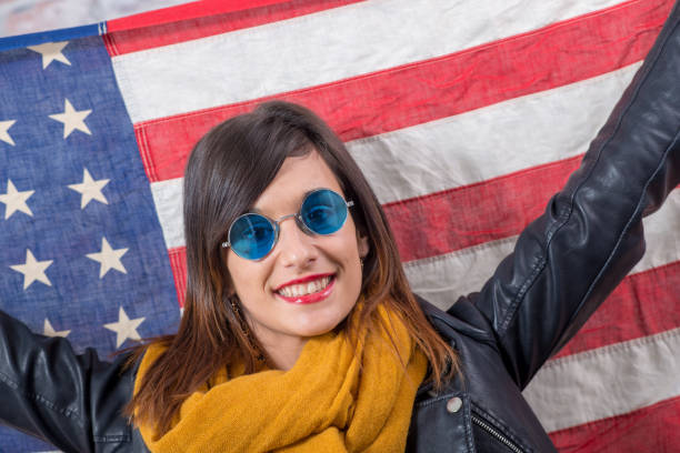 istock young brunette with blue sunglasses in front of  american flag 945558464