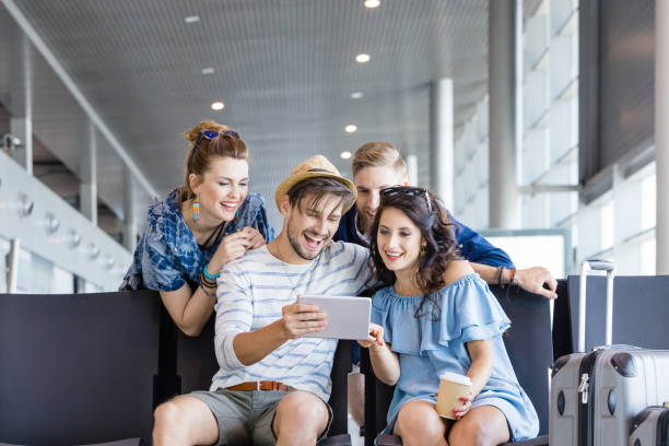 istock Friends using digital tablet at waiting lounge in airport 945563614