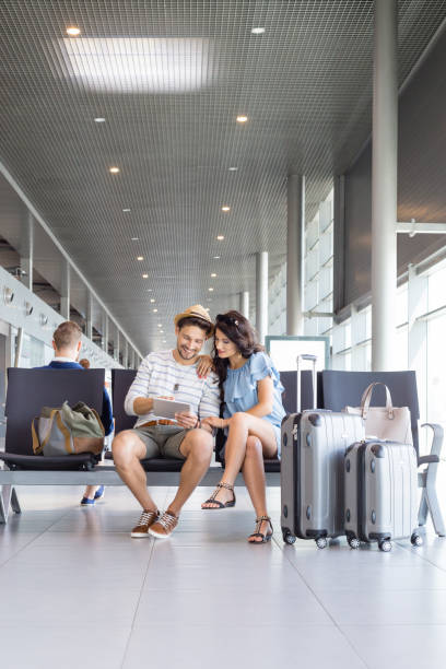 Couple using digital tablet in airport lounge