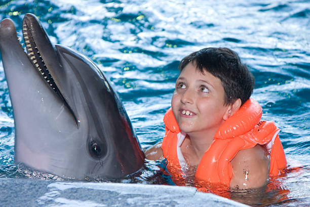 istock The boy floats in water with a dolphin 94557742