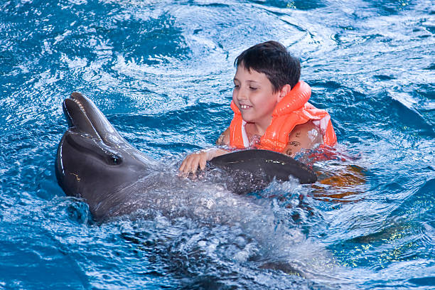 istock The boy floats in water with a dolphin 94557745