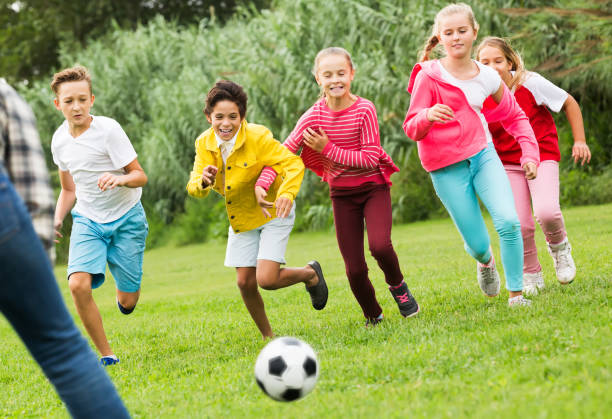 istock Kids playing football in park 945584352